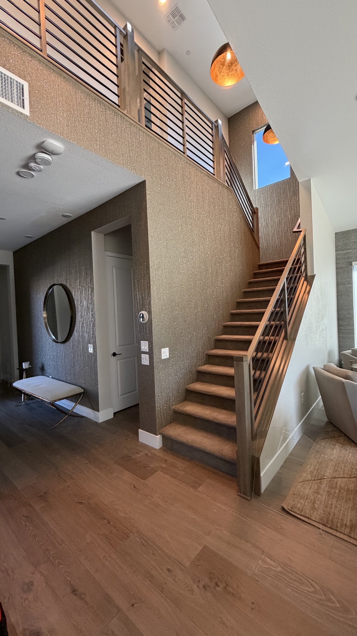 Staircase foyer with bronze wallcovering and warm lighting