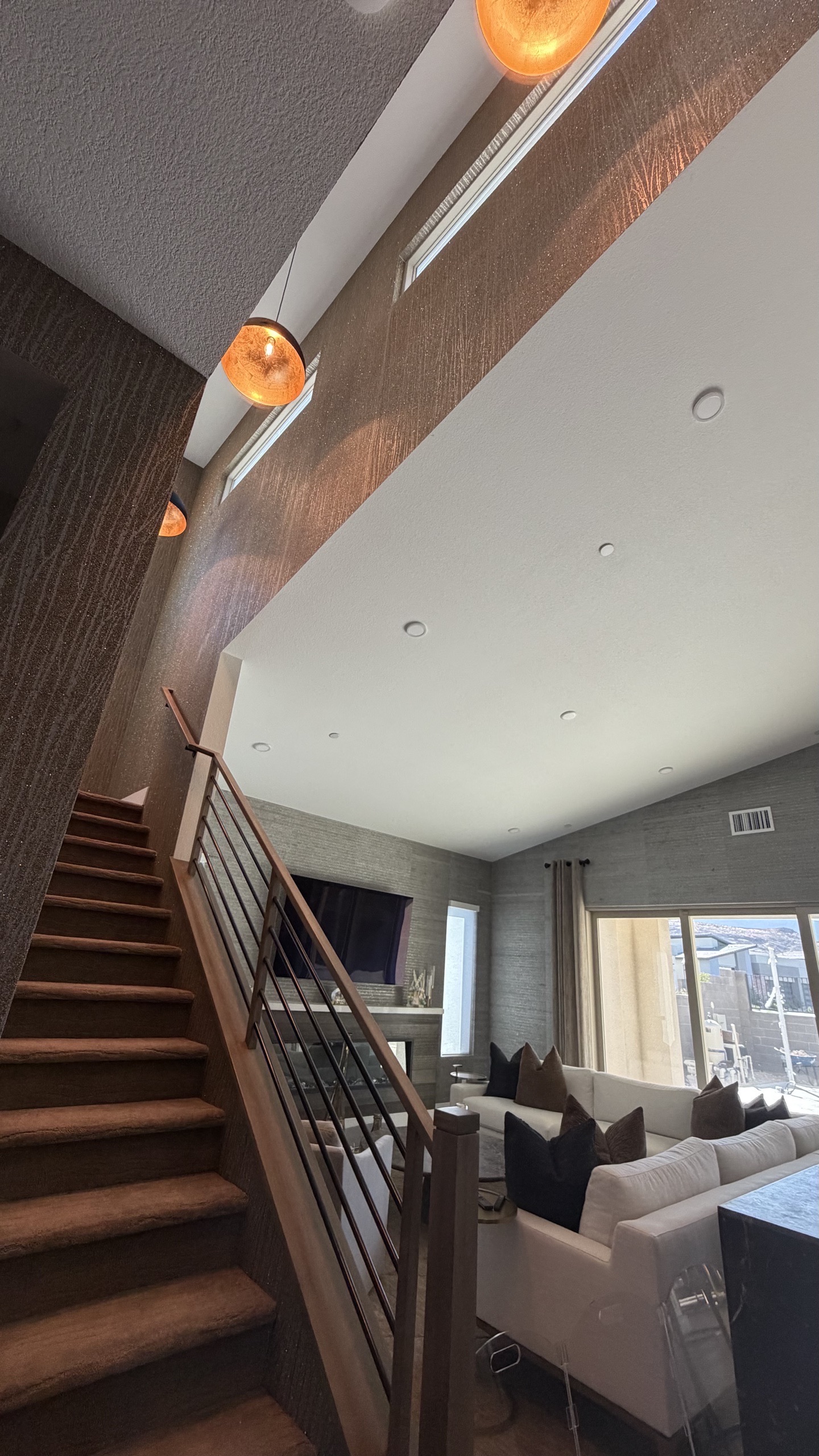 Dramatic staircase with warm pendant lighting and textured wallcovering